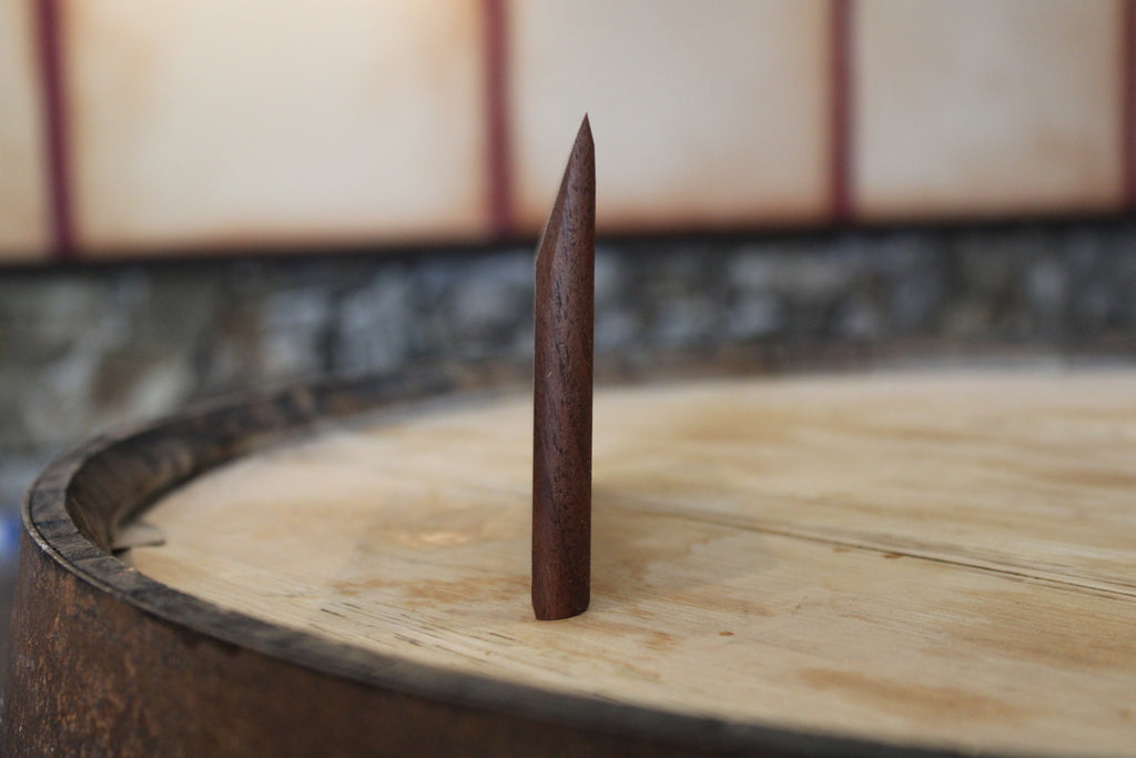 Tapered wooden bench scraper standing up to show angled profile.