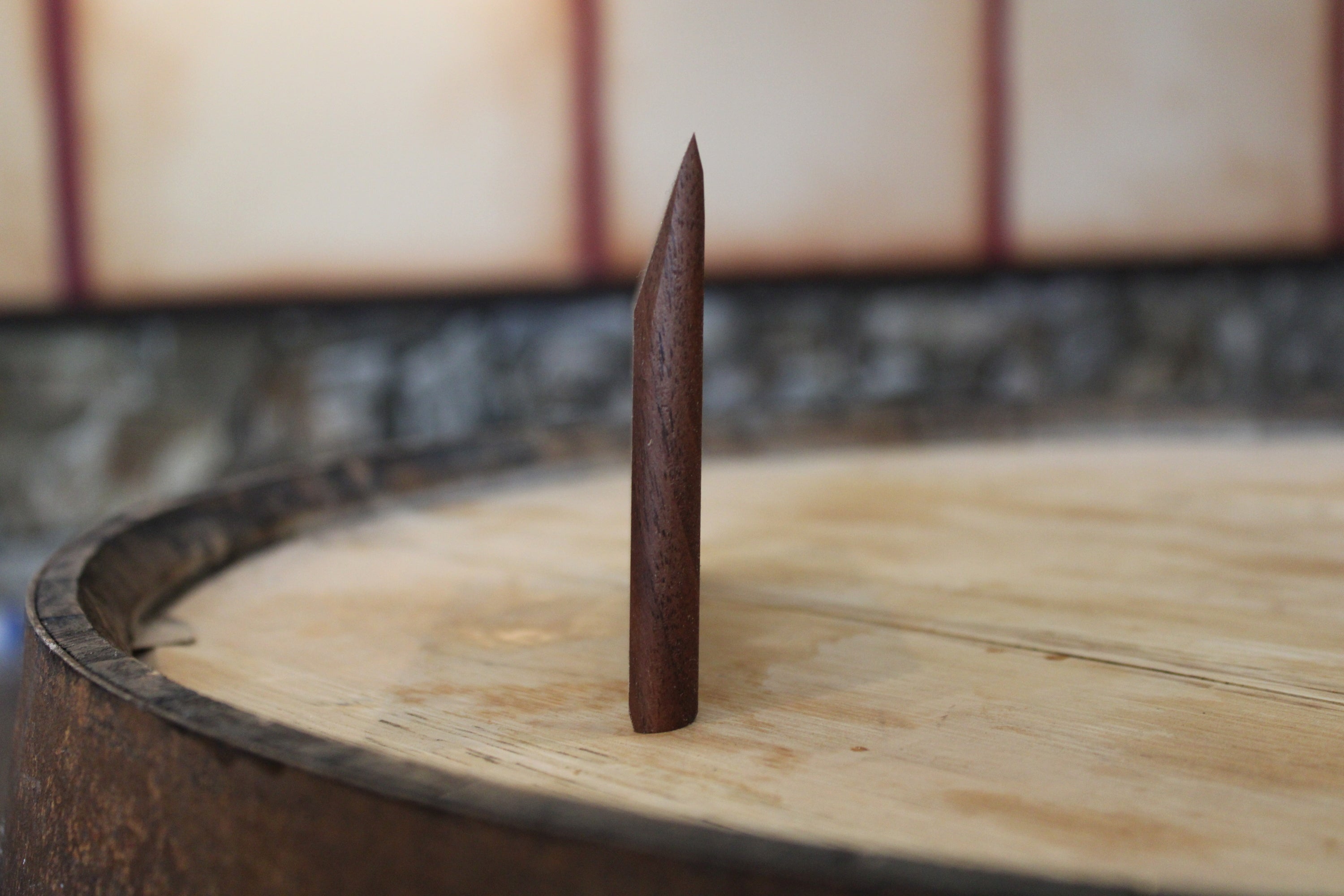 Tapered wooden bench scraper standing up to show angled profile.